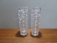 Front view of two matching clear Czech glass vases with geometric textured patterns, placed on wooden surface.