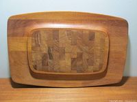 Front view of the rectangular teak board with a raised center portion featuring end grain wood pattern.