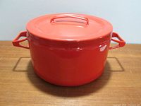 Photo of red stock pot with lid on, showing exterior and metal handle on lid.