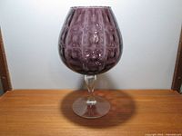 Full front view of the purple textured fishbowl shaped glass vase on clear footed stem