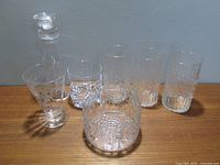 Full set of glassware and candlestick holder arranged on a wooden surface against a gray wall.
