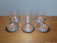Six clear glass rocks glasses arranged on a surface showing the Pisararengas pattern from above at an angle.