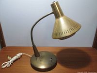 Side view of brass mid century desk lamp with gooseneck and original perforated diffuser, showing the full lamp and coiled cord.