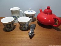 Wide view of coffee set with two mugs, creamer, covered sugar bowl in Tor Viking pattern and Flowerdale red teapot with small metal utensil on table