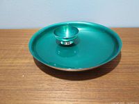 Photo of round green enamel tray with slightly raised edge and silver rim.