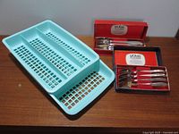 Two-tier aqua blue plastic cutlery holder with perforated panels, alongside two original boxed sets of Splayds in different sizes.