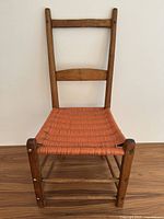 Front view of the antique Quebecois pine chair showing woven seat and wooden frame with square nails.
