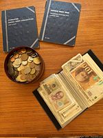 Two blue coin albums for Canadian and US pennies, vintage leather box filled with coins and photo album with international banknotes visible