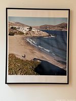 Front view of the large framed seaside landscape photo with a beach, sea, and hills in Greece.