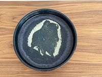 Top view of large black glazed pottery bowl with buffalo design in center.