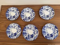 Six Royal Crown Derby Mikado pattern dessert plates displayed topside, showing detailed blue and white scenic design with gold rim.