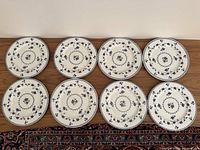 Eight Royal Doulton Yorktown blue and white translucent china dinner plates arranged in two rows of four on a wooden surface.