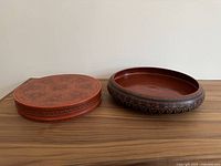 Two pieces: lidded box on left with etched designs, open bowl on right with black floral etchings on rim.