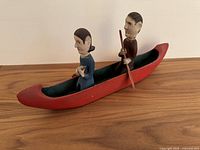 Red canoe with seated wooden figures