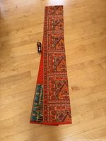 Full length of the colorful silk fukuro obi with woven patterns section and plain vibrant orange section.