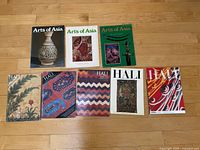 Eight vintage magazines grouped on floor, three 'Arts of Asia' and five 'Hali' magazines with colorful artistic covers showing ceramics, textile patterns, and Asian art.