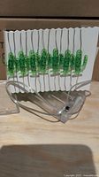 Close-up of a single light string showing green translucent cactus-shaped lights on clear wiring with battery pack