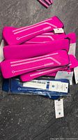 Grouped pink and blue soft cases for reusable steel straws with brushes, stacked on surface