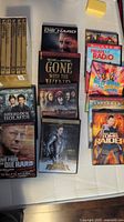 Photo of various DVD and Blu-ray cases arranged on a white surface showing titles such as Die Hard, Gone with the Wind, Pirates of the Caribbean, Sherlock Holmes, and more.