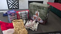 Photo of assorted Christmas items including Santa hat, gold stocking, Christmas crackers boxes and loose crackers, boxed candle set on table