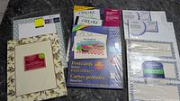Photo showing multiple packages of paper including postcards, certificates, and CD inserts laid flat on table