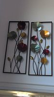 Two metal flower wall hangings mounted side by side, showing overall size and design.