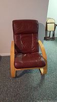 Front view of red leather armchair with molded wooden frame and padded seat and backrest.