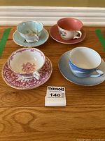 Overhead view of four assorted porcelain cups and saucers placed on wooden surface