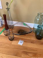 Photo of the assortment of glass pieces including a triangular smoked glass bowl signed Holmgaard, vases, and small bowls.