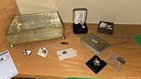 Photo of entire lot showing the jewelry box, con purse, and various lapel pins laid out on a wooden surface