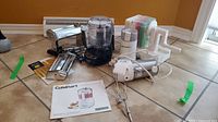 Overview of all items in the lot including the food processor, pasta maker, hand mixer, and grater with instruction manual on floor.