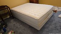 Full view of queen pillow-top mattress with box spring placed on carpeted floor.