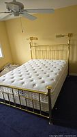 Full assembled queen bed showing gold-tone metal frame with mattress in bedroom setting