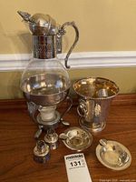 Photo showing entire lot with glass carafe on silver stand, ice bucket, two burner supports, and two ashtrays on wooden surface.