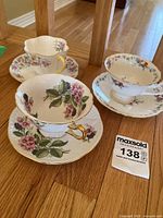 Photo showing three Shelley China teacups with floral patterns and matching saucers on a wooden table.