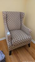 Side angled view of the fabric wing accent chair on wood floor.