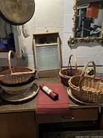 Photo showing wooden antique washboard, wicker gift baskets, and rolled silicone baking mats on a wooden table.