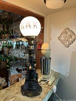 Photo of bar light with figurine base holding lamppost, showing white globe lamp with 'BAR' lettering.