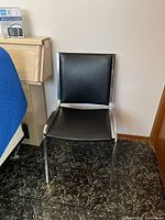 Front view of a black vinyl and chrome office chair with some discoloration on the backrest