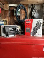 Overview photo showing the Black & Decker jig saw, Jobmate tool kit box, coiled black wire cable in the background, all placed on a red surface.