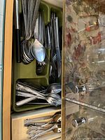 Top drawer with assorted forks, spoons, and knives arranged in a plastic cutlery tray inside a wooden drawer.