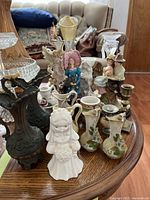 Front view showing a variety of figurines including angels, period dress figures, and small decorative pitchers arranged on a wooden table
