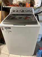 Front view of GE top load washing machine showing white exterior and glass lid
