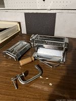 Imperia pasta maker with detachable wooden handle and metal clamp on wooden surface