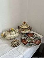 Photo of two ceramic serving dishes and a decorative plate on a white table against a wall