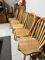 Five light oak kitchen chairs angled in a row showing the curved backs and seats.