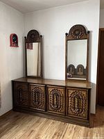 Front view of the dresser showing two tall mirrors with carved wooden tops and six drawers with carved detailing.