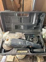 Rona angle grinder inside carrying case with grinding disc attached and additional accessories visible