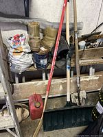 Photo showing the hockey stick, snow shovel, spade shovel, and red gas can grouped together in garage environment.