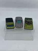 Front view of three vintage Hot Wheels Redline cars showing their condition and colors.